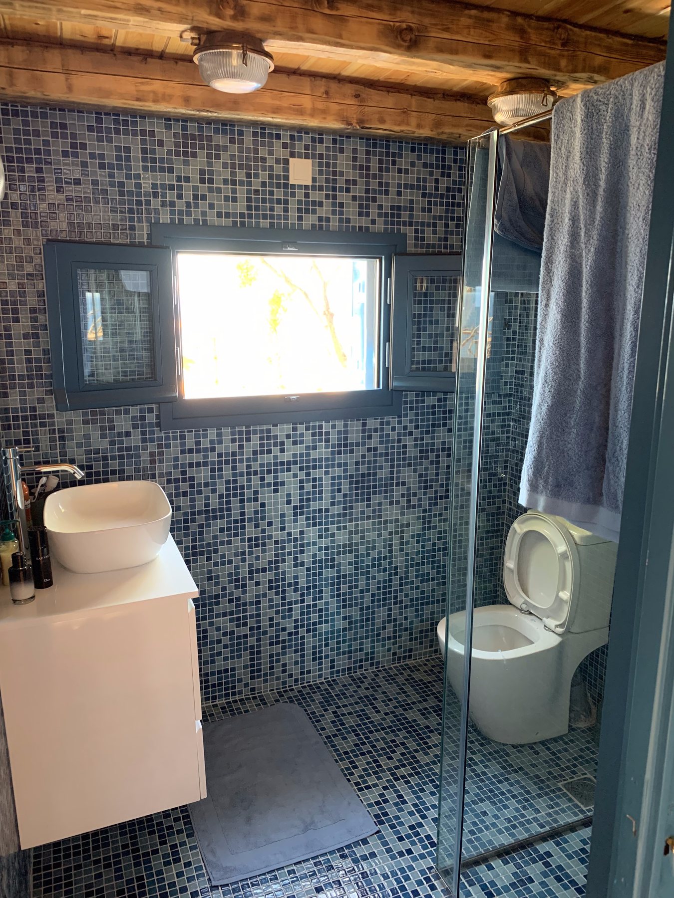 Blue mosaic bathroom with WC, vessel basin and shower