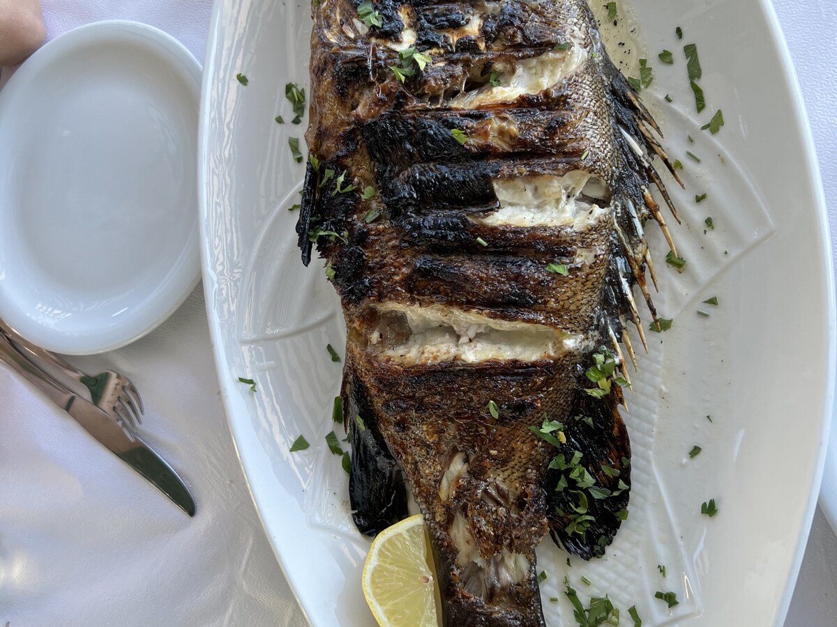 Whole grilled fish with lemon, served with a Mythos glass