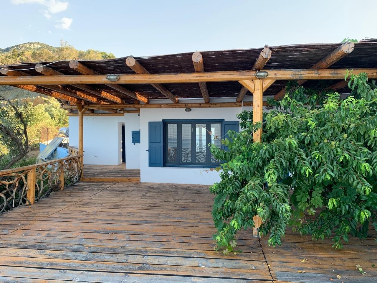 Whitewashed unit with blue-framed windows and a pergola over the deck