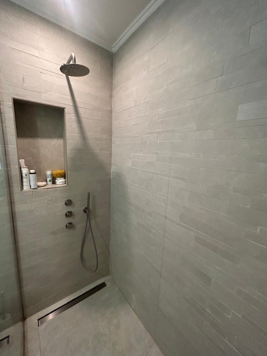 Guest suite en-suite — stone-tile walk-in shower with rainfall and handheld heads