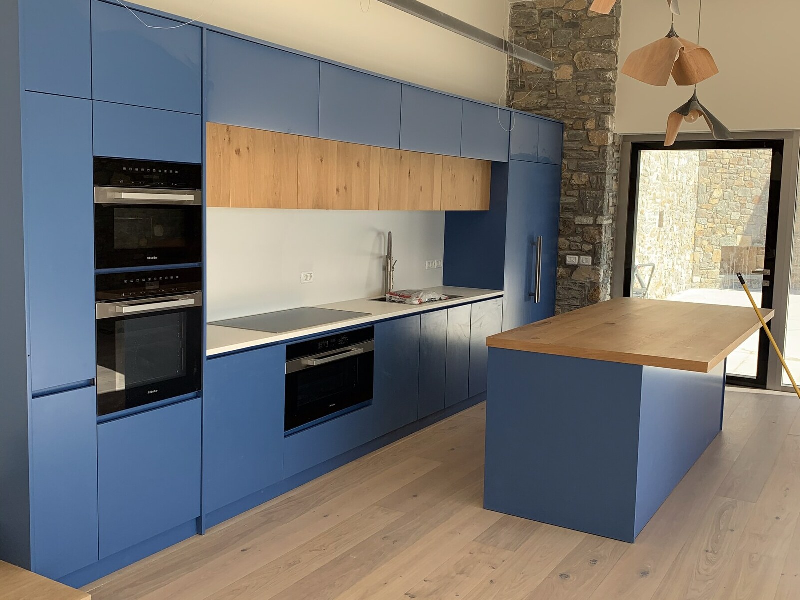 Wider view of the Miele kitchen, stone wall and oak island